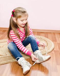 cute-little-girl-tying-her-white-shoes-home-36213353